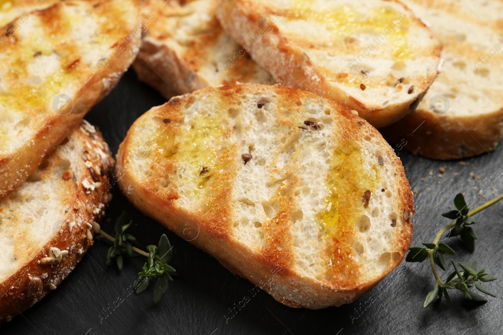 Photo of Tasty bruschettas with oil and thyme on black table, closeup