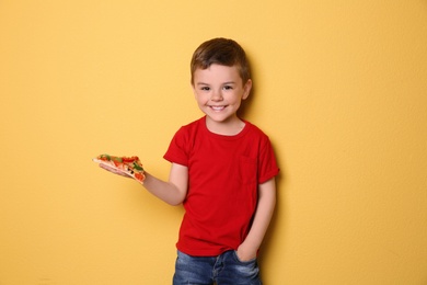 Photo of Cute little boy with slice of pizza on color background