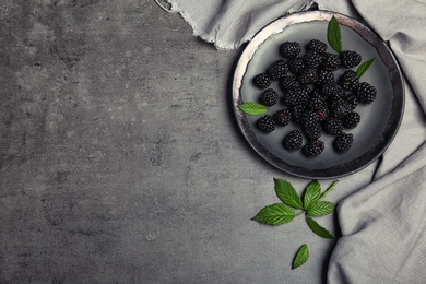 Photo of Flat lay composition with plate of fresh blackberry and space for text on gray background