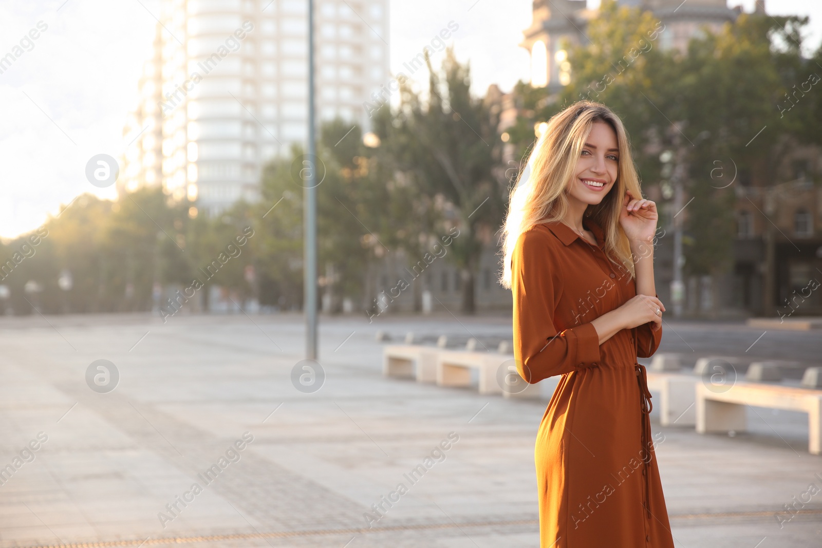 Photo of Beautiful young woman in stylish red dress on city street