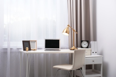 Photo of Stylish workplace with laptop on table in office