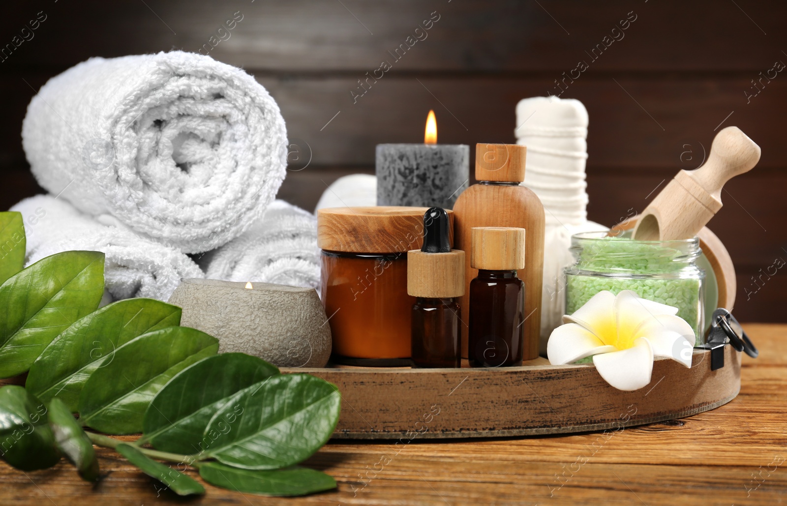 Photo of Spa composition with herbal bags, cosmetics and towels on wooden table