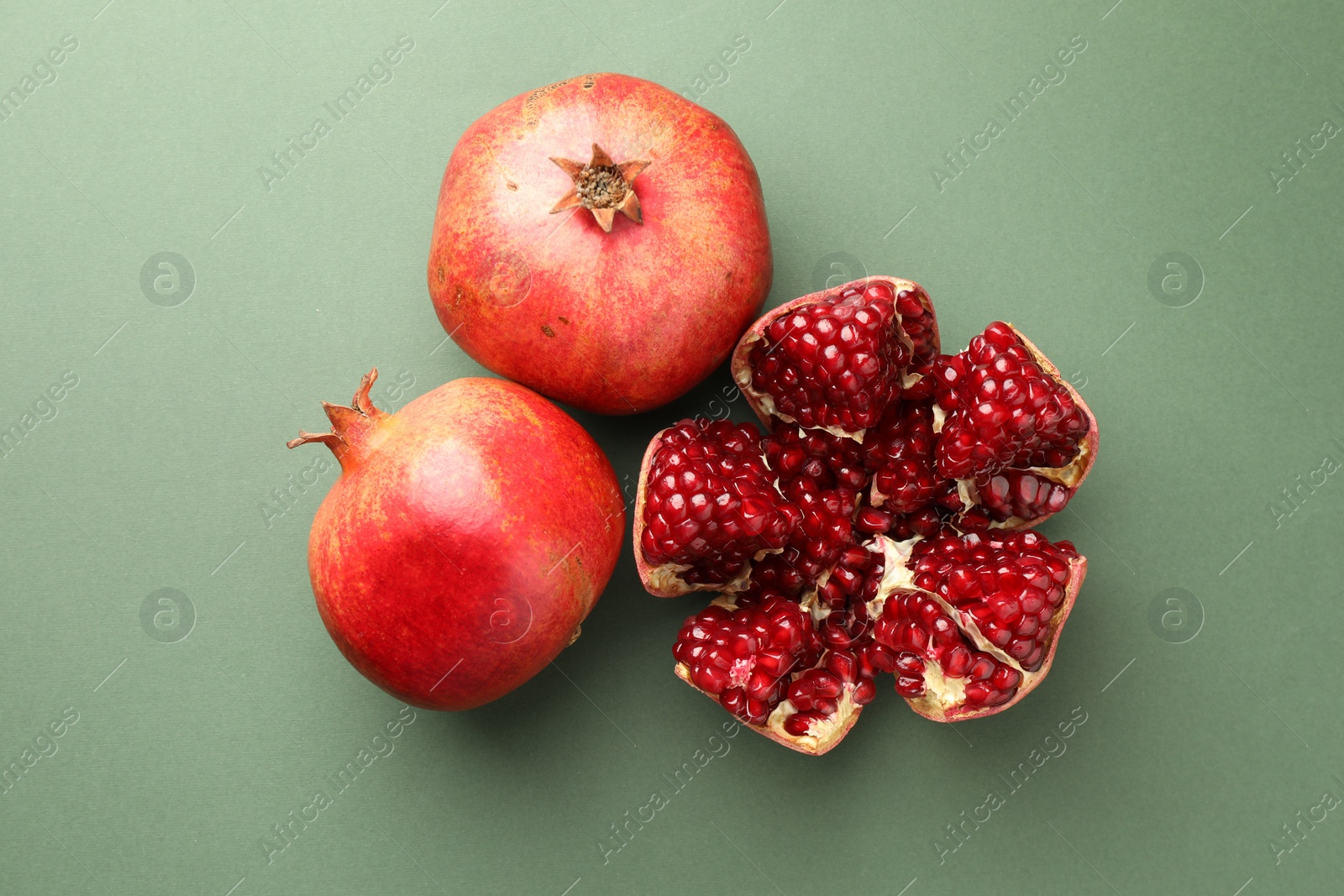 Photo of Fresh ripe pomegranates on pale green background, top view