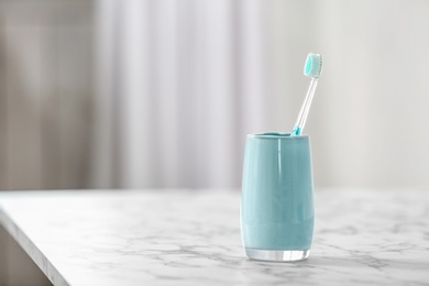 Photo of Cup with toothbrush on table. Dental care