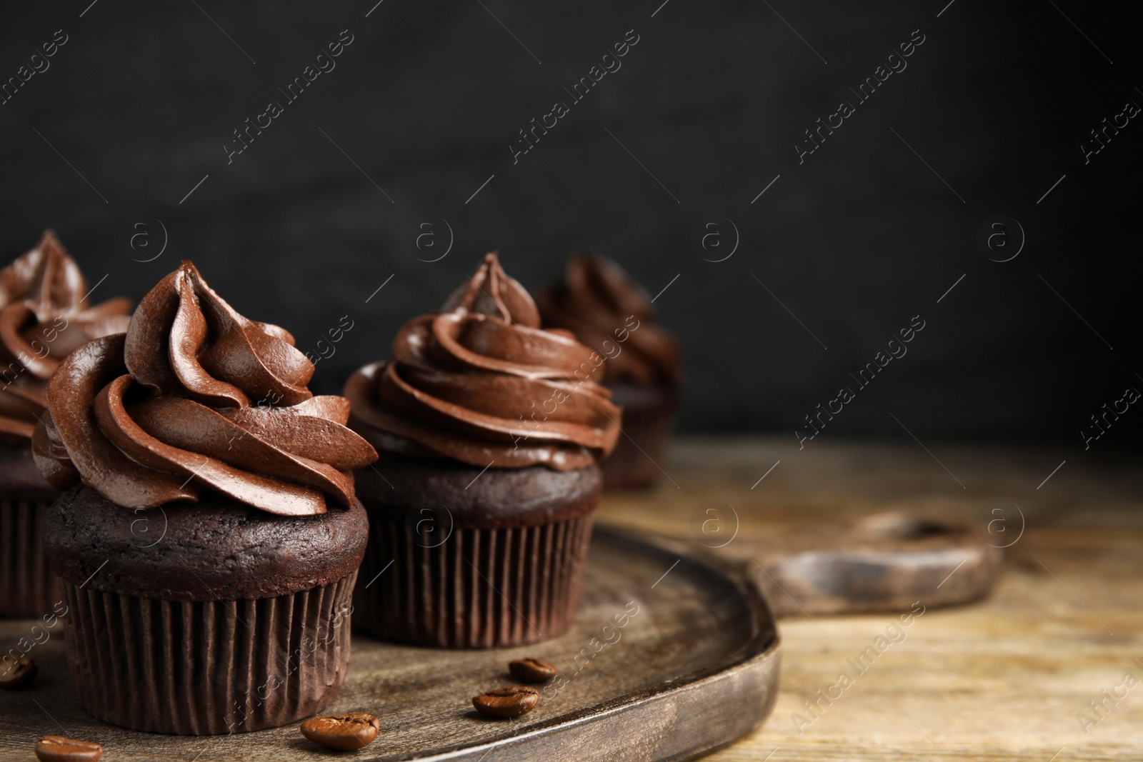 Photo of Delicious chocolate cupcakes with cream on wooden table. Space for text