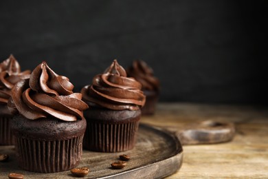 Photo of Delicious chocolate cupcakes with cream on wooden table. Space for text