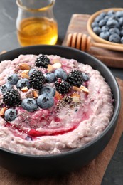 Photo of Tasty oatmeal porridge with toppings in bowl served on table