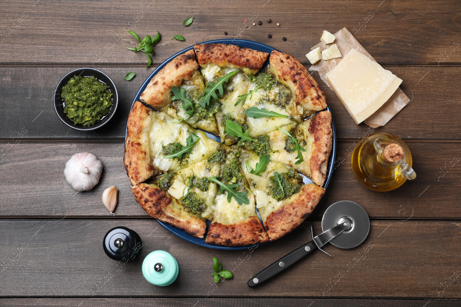 Photo of Delicious pizza with pesto, cheese and arugula served on wooden table, flat lay