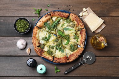 Delicious pizza with pesto, cheese and arugula served on wooden table, flat lay