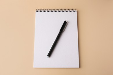 Notepad with erasable pen on beige background, top view