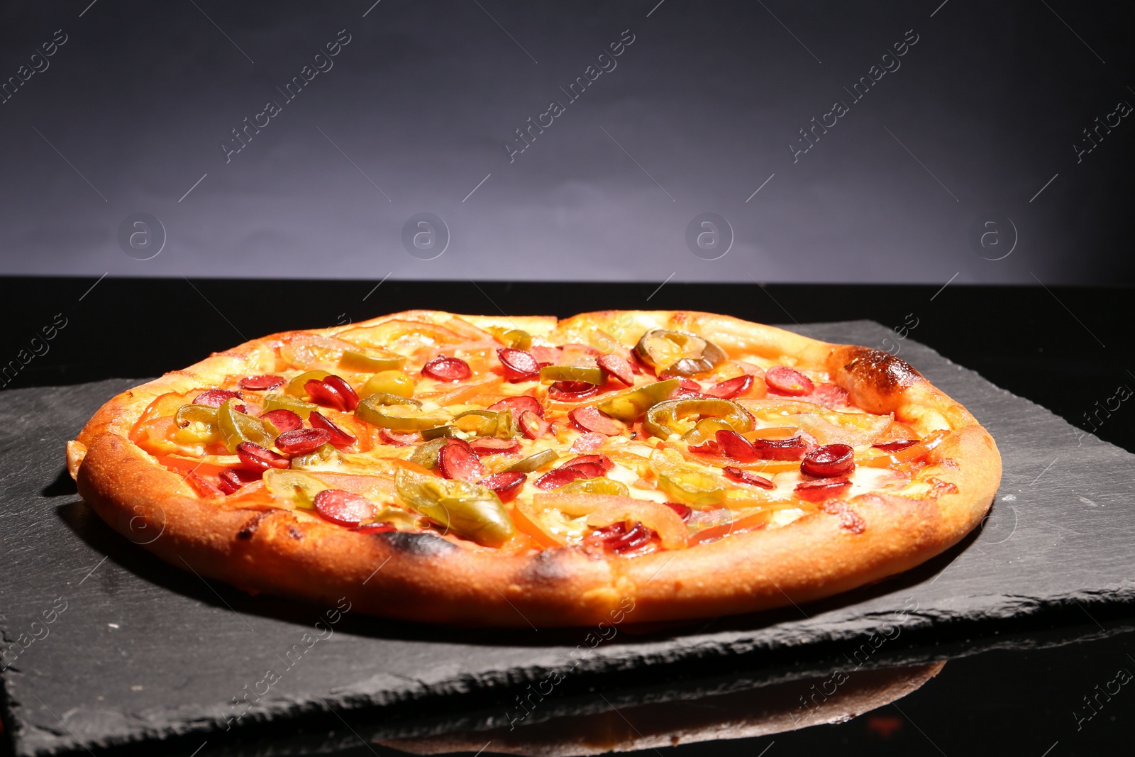 Photo of Delicious pizza Diablo on slate board against grey background