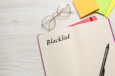 Word Blacklist written in notepad and paper notes on white wooden table, flat lay