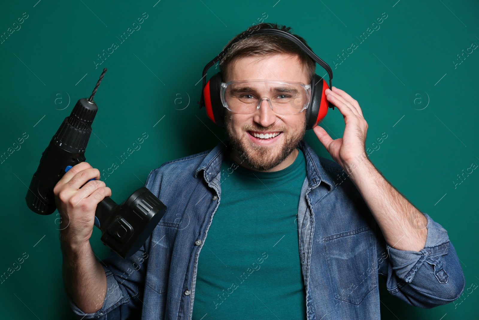 Photo of Young working man with power drill on green background