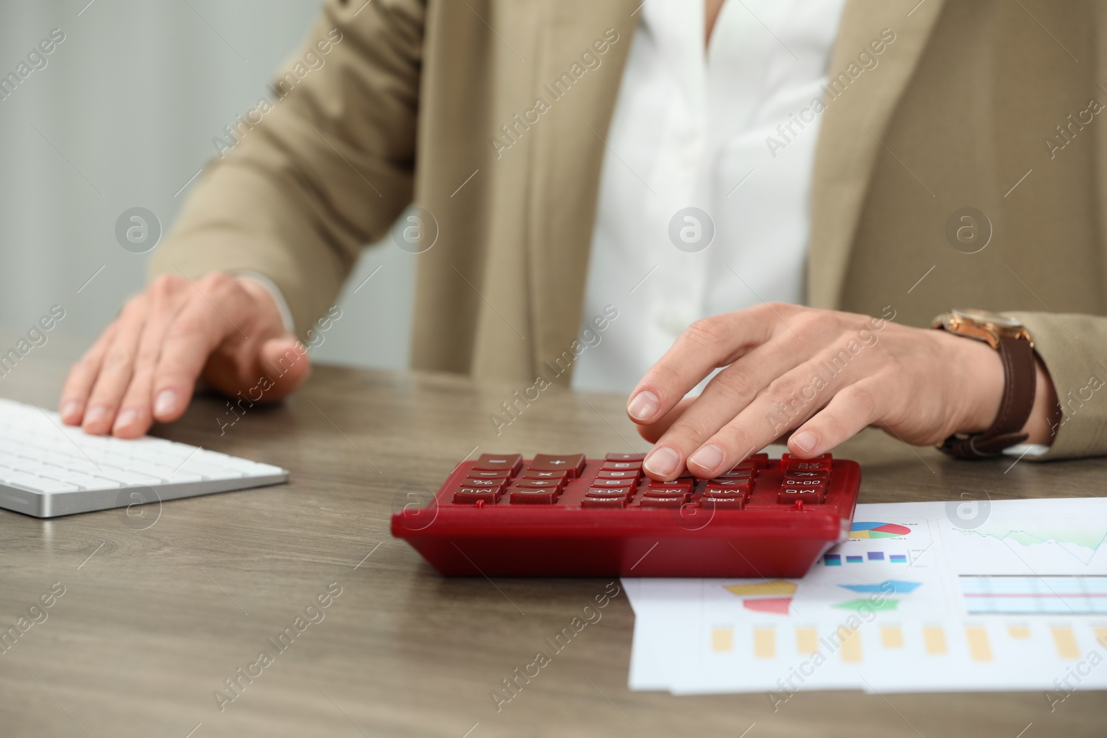 Photo of Professional accountant using calculator at wooden desk in office, closeup