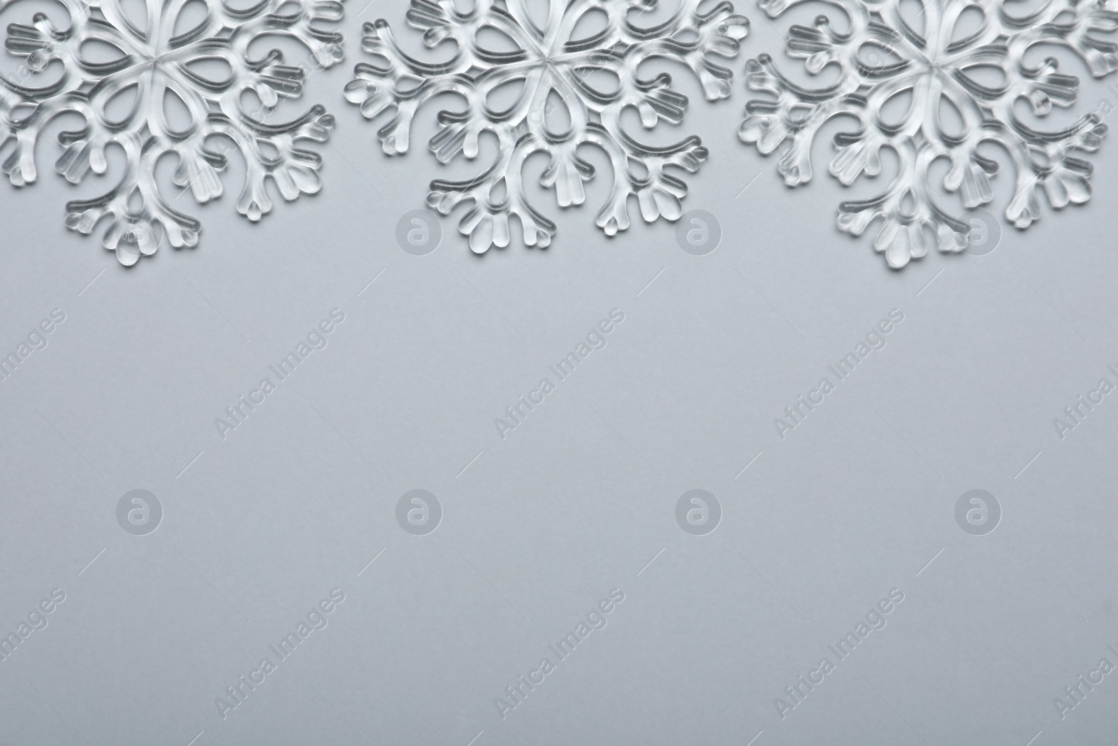 Photo of Beautiful decorative snowflakes on light grey background, flat lay. Space for text