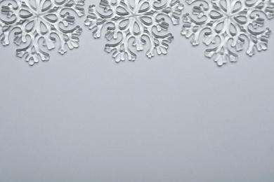 Beautiful decorative snowflakes on light grey background, flat lay. Space for text