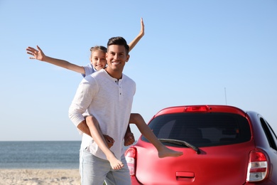 Photo of Father and daughter near car at beach. Family vacation