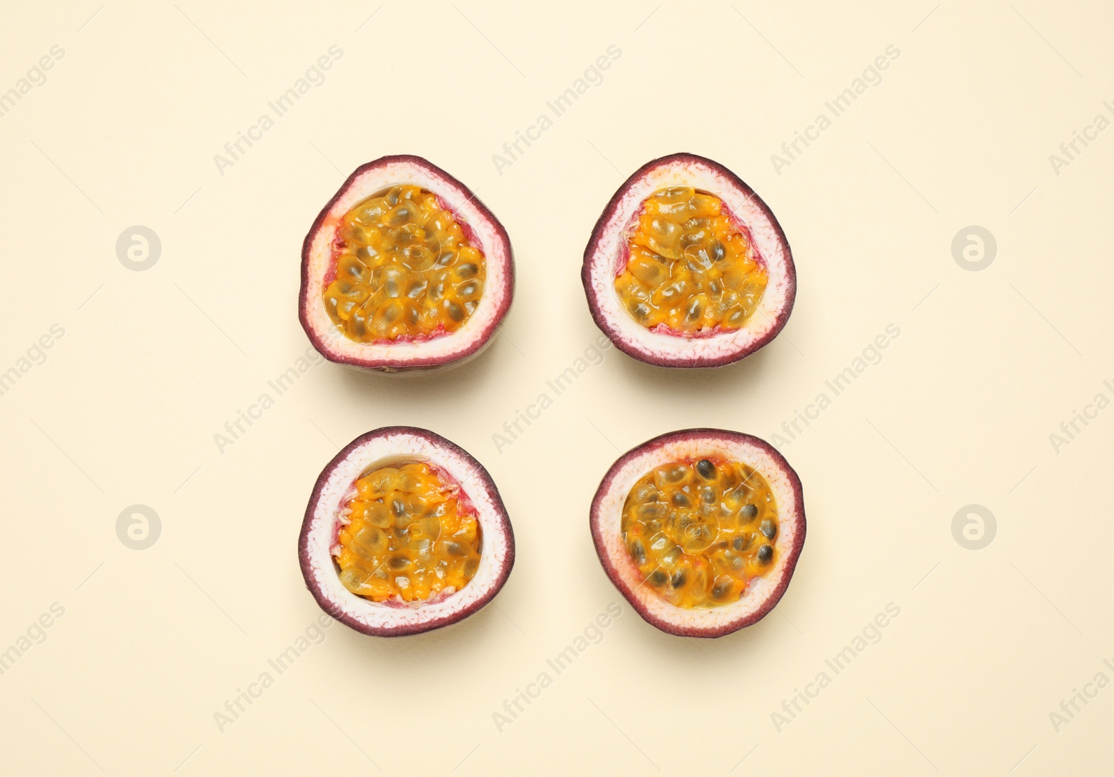 Photo of Halves of fresh ripe passion fruits (maracuyas) on beige background, flat lay
