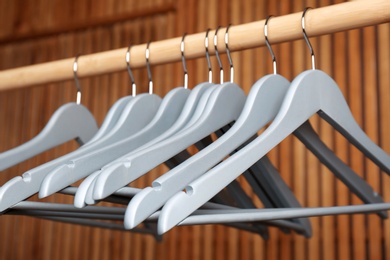 Photo of Empty hangers on rail against wooden background