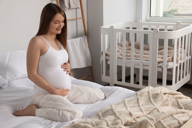 Photo of Happy young pregnant woman in pajamas on bed at home