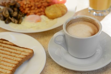 Cup of coffee and delicious breakfast served on beige table, closeup