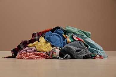 Photo of Pile of dirty clothes on floor near light brown wall indoors