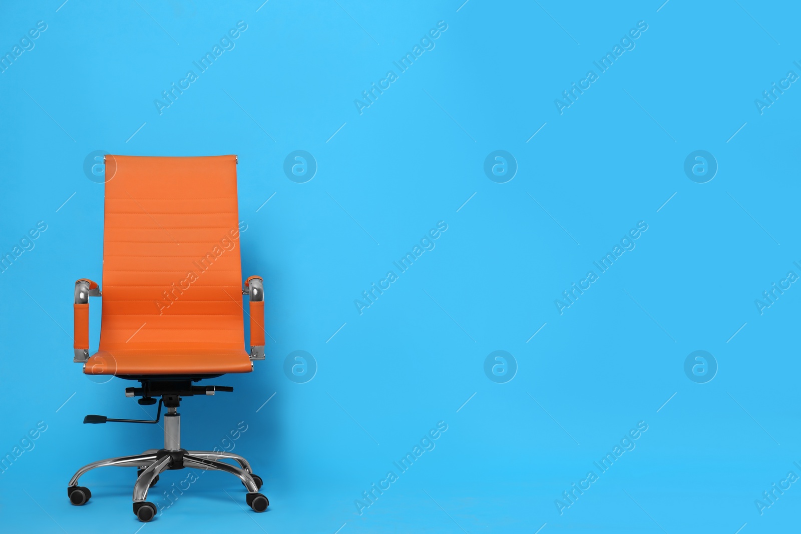 Photo of Comfortable office chair on light blue background, space for text