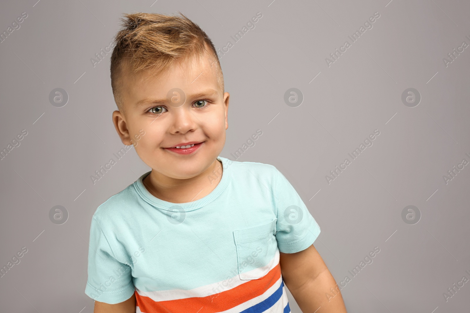 Photo of Cute little boy posing on grey background