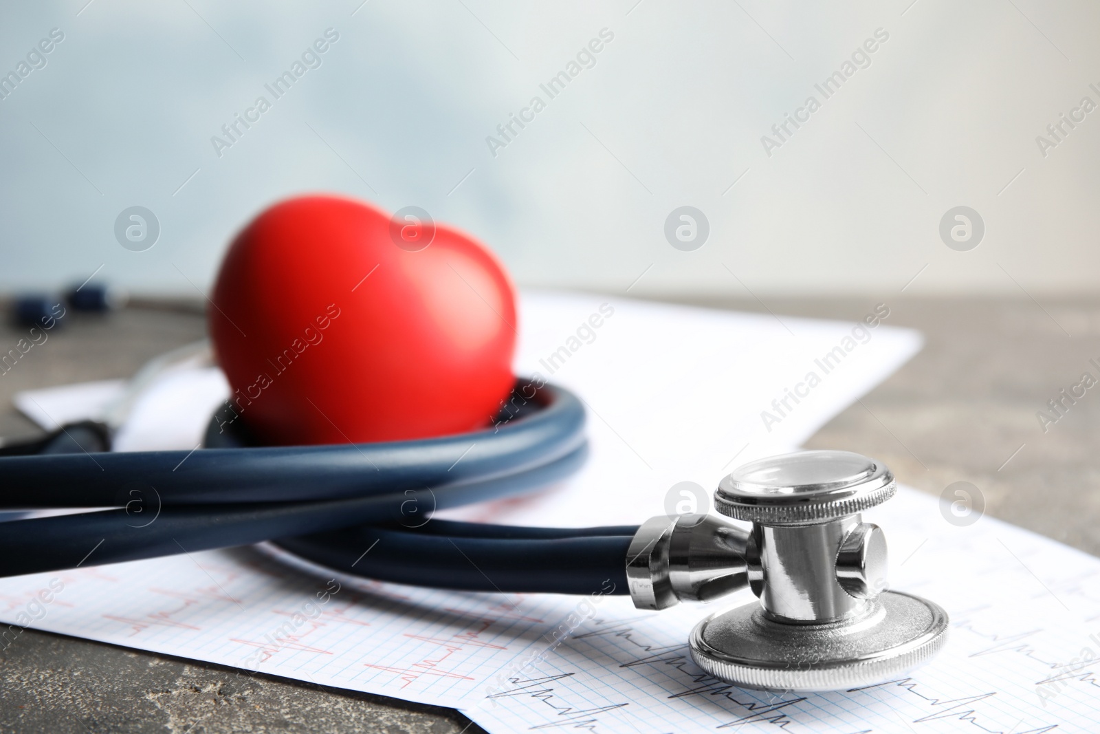 Photo of Stethoscope, red heart and cardiogram on gray table. Cardiology concept