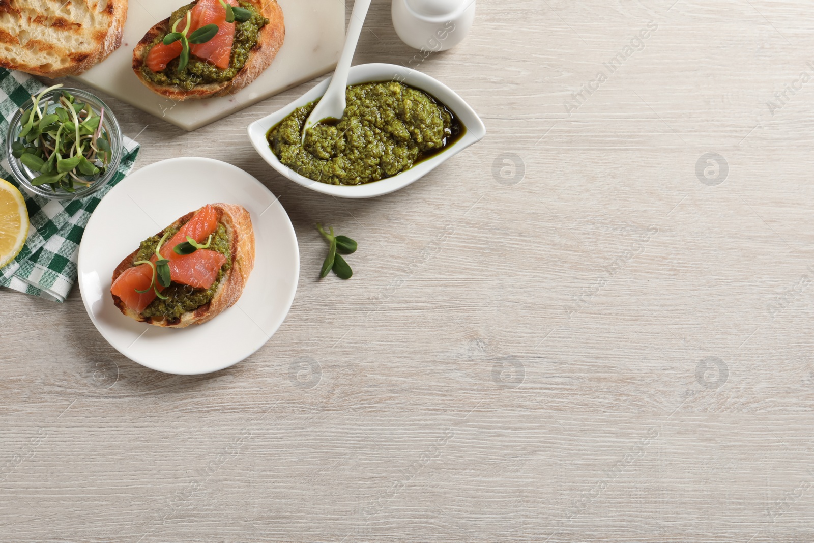 Photo of Delicious bruschettas with salmon and pesto sauce on wooden table, flat lay. Space for text