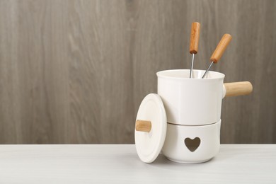 Photo of Fondue set on white wooden table, space for text