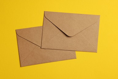 Photo of Envelopes made of parchment paper on yellow background, flat lay