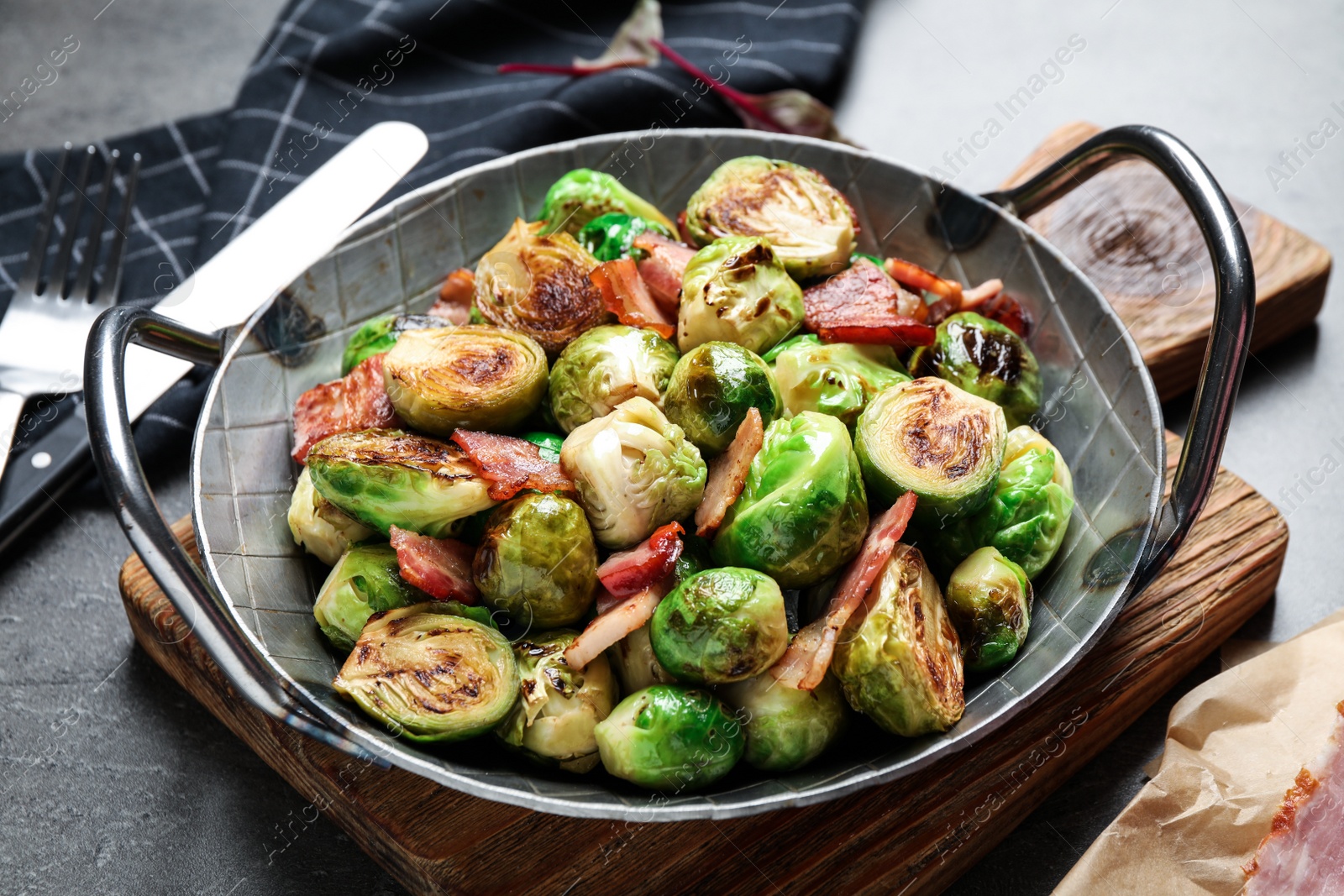 Photo of Delicious Brussels sprouts with bacon served on grey table