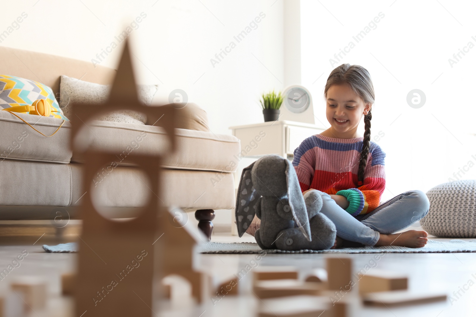 Photo of Cute little child playing with wooden building blocks on floor indoors. Space for text