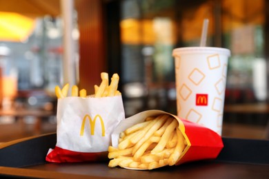 MYKOLAIV, UKRAINE - AUGUST 11, 2021: Big and small portions of McDonald's French fries near drink on tray in cafe