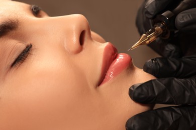 Young woman undergoing procedure of permanent lip makeup in tattoo salon, closeup