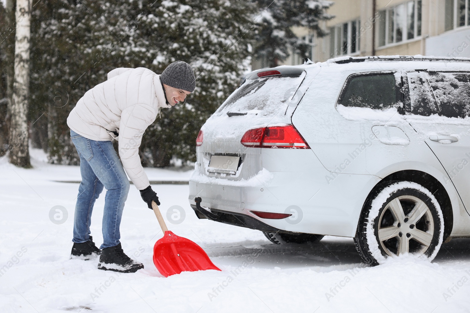 Photo of Man removing snow with shovel near car outdoors