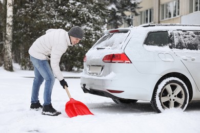 Man removing snow with shovel near car outdoors