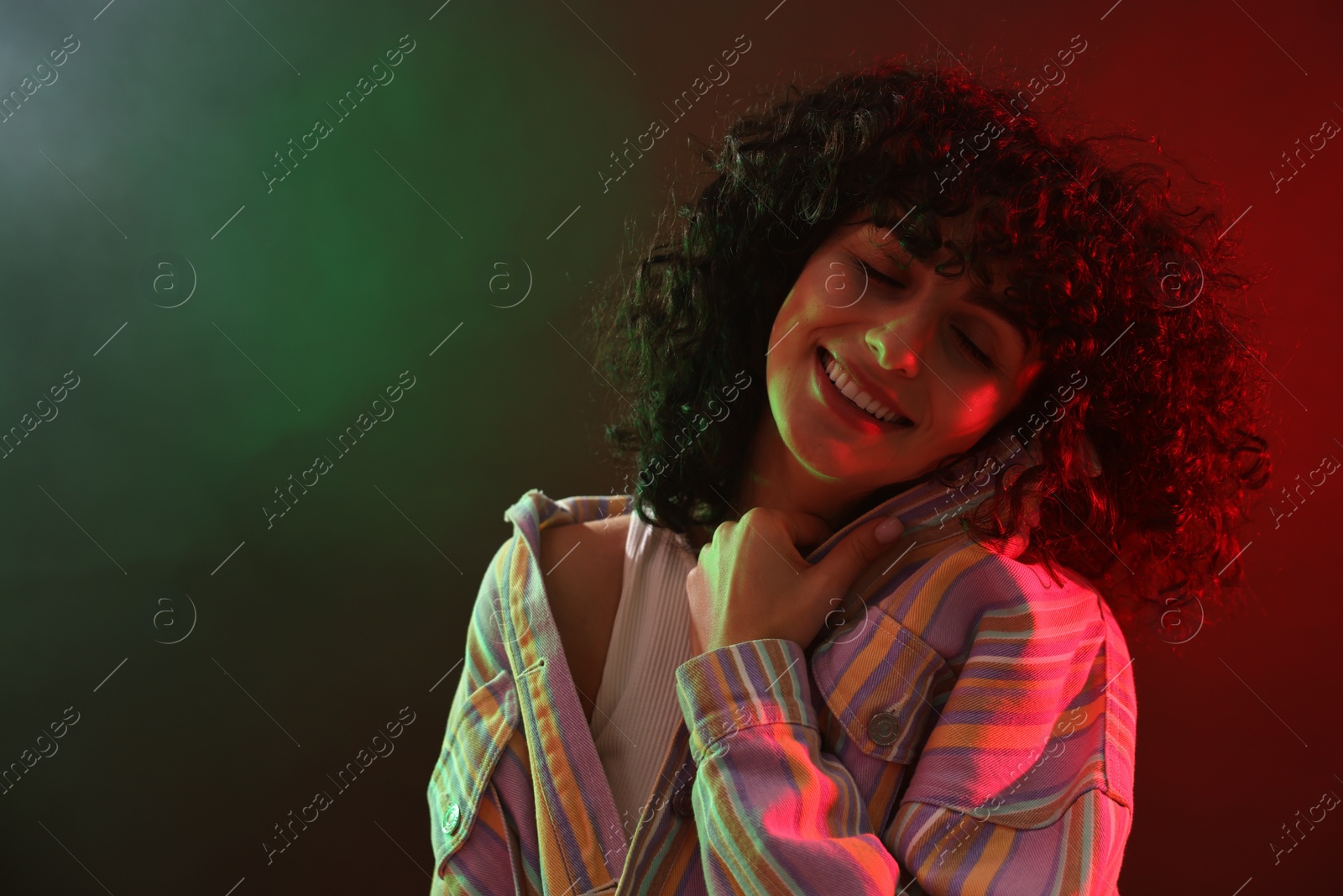 Photo of Beautiful young woman posing on color background in neon lights. Space for text