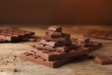 Photo of Pieces and crumbs of tasty chocolate on wooden table