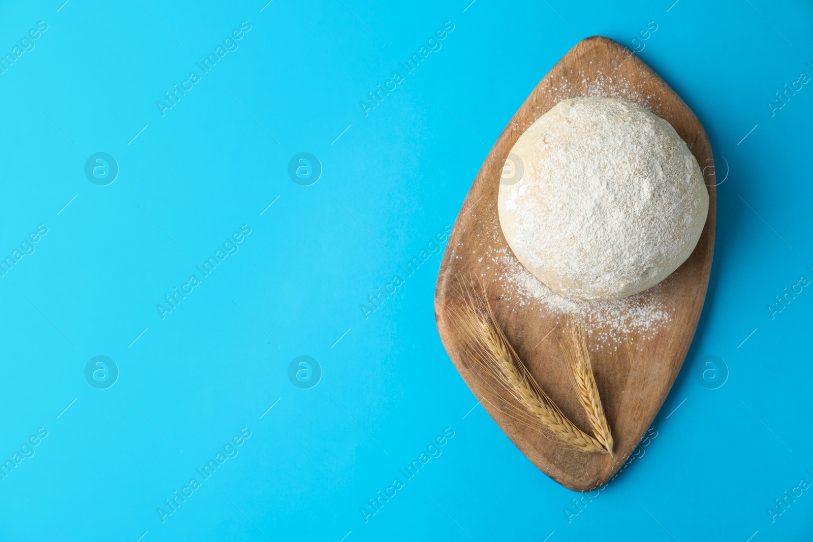 Photo of Dough and spikelets on light blue background, top view with space for text. Cooking pastries