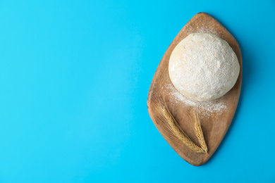 Dough and spikelets on light blue background, top view with space for text. Cooking pastries