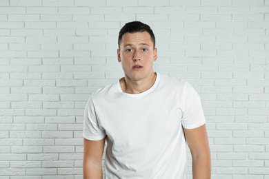 Photo of Handsome young man near white brick wall