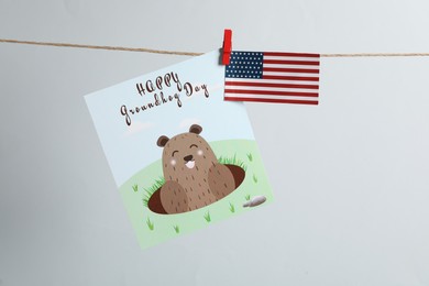 Happy Groundhog Day greeting card and American flag hanging on light background