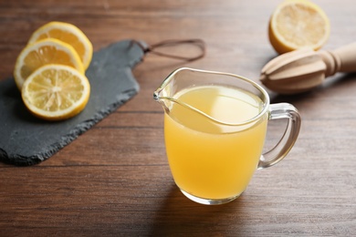 Photo of Glass jug with fresh lemon juice on wooden table