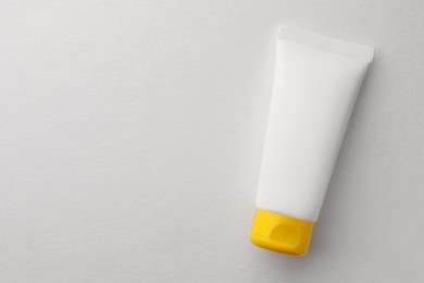 Tube of face cream on white background, top view. Space for text