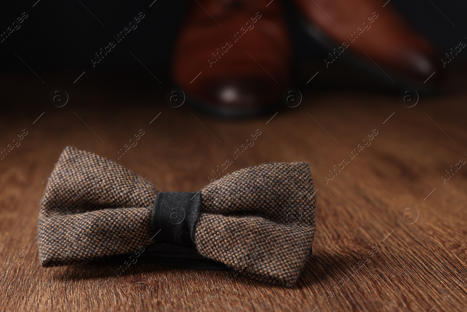 Photo of Stylish brown bow tie on wooden table, space for text