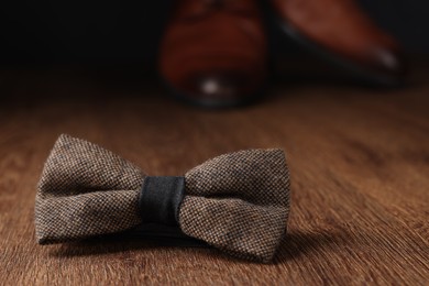 Stylish brown bow tie on wooden table, space for text