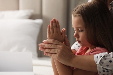 Photo of Mature woman with her little granddaughter praying together at home