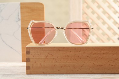 Stylish sunglasses on white wooden table. Summer accessory